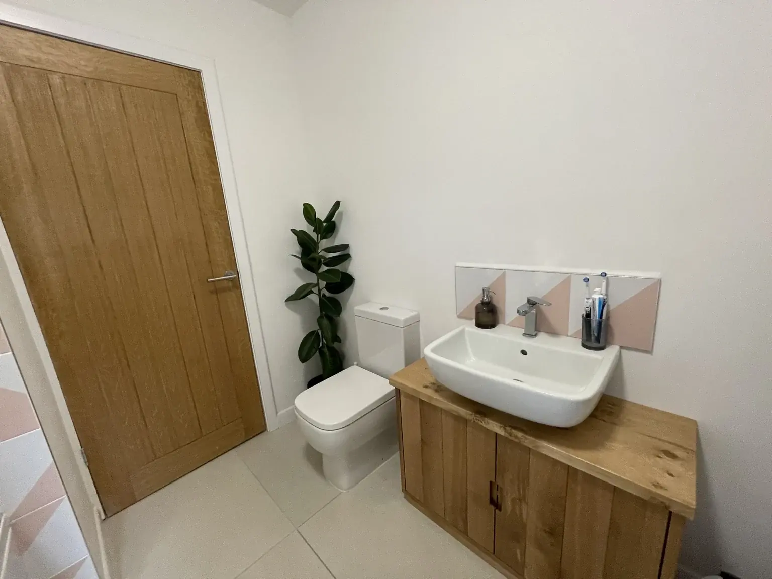 White countertop basin on a timber vanity cabinet, with matching geometric splashback tiles.