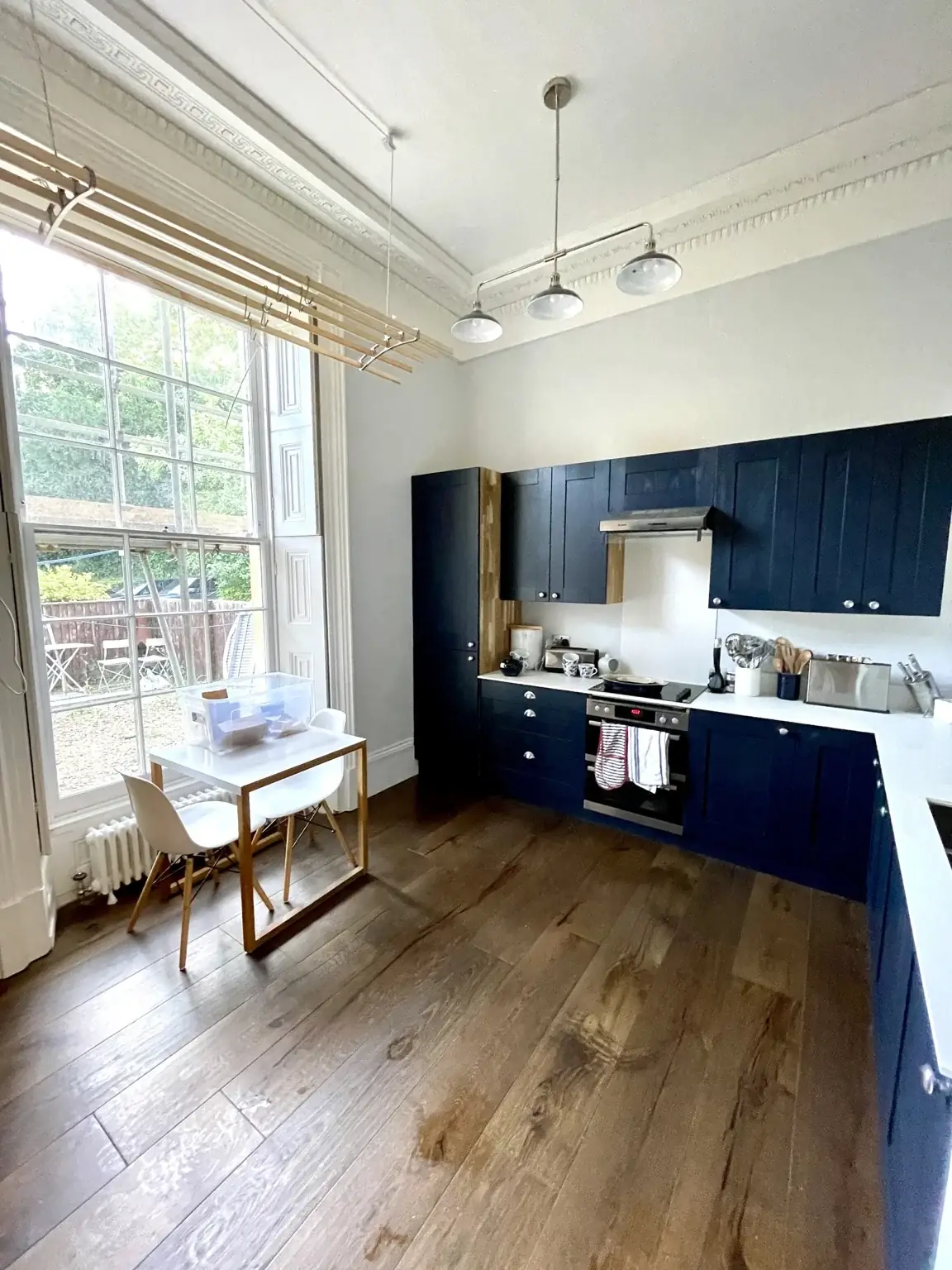 Dark blue solid oak kitchen cabinets with white worktops and walnut flooring.