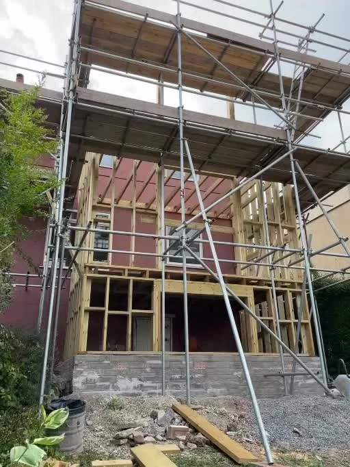 Exposed multi-storey timber frame behind scaffolding during construction in Knowle.