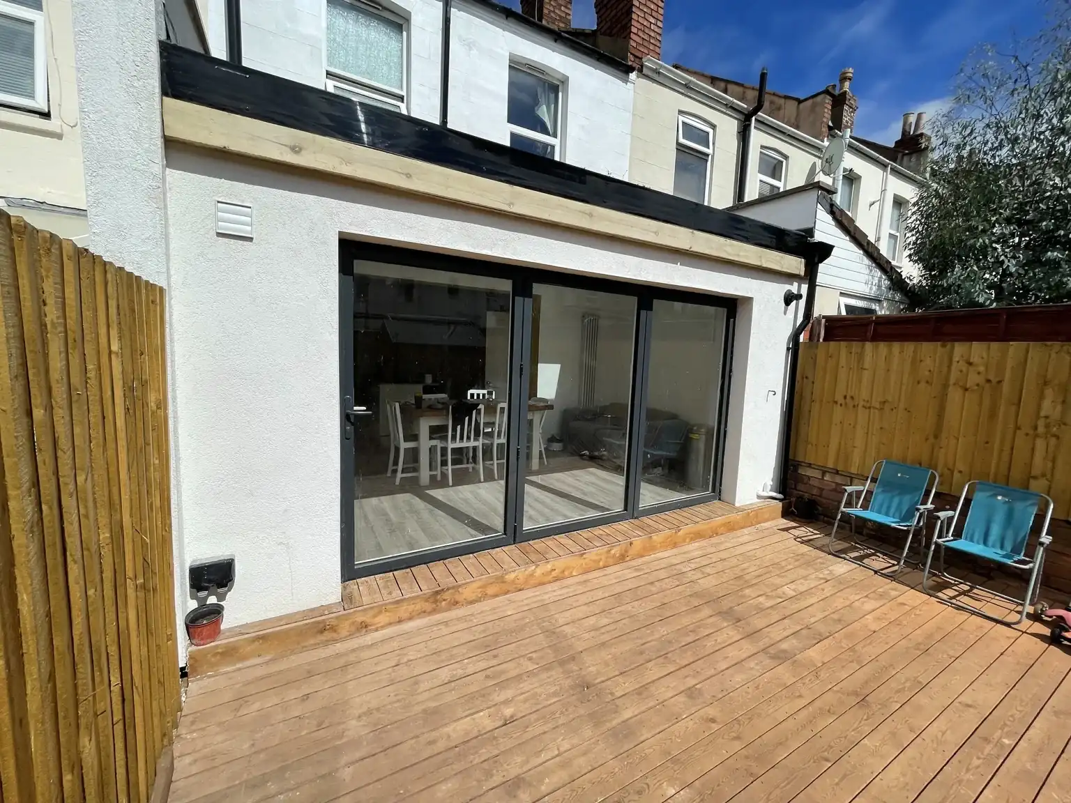 Rear extension with white render, glazed doors and timber decking.