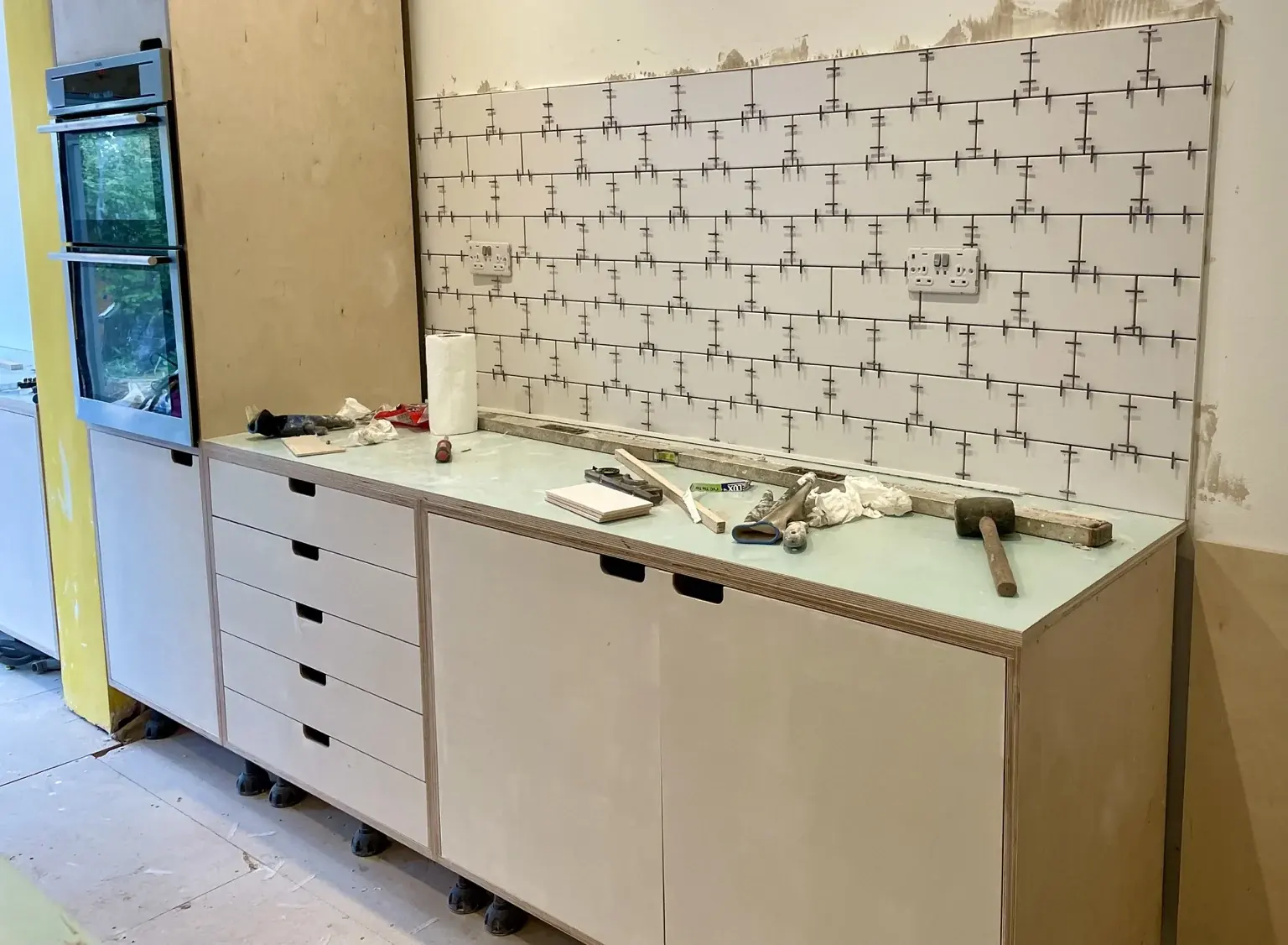 Kitchen cabinetry and timber worktop during installation, before the tiled splashback was completed.