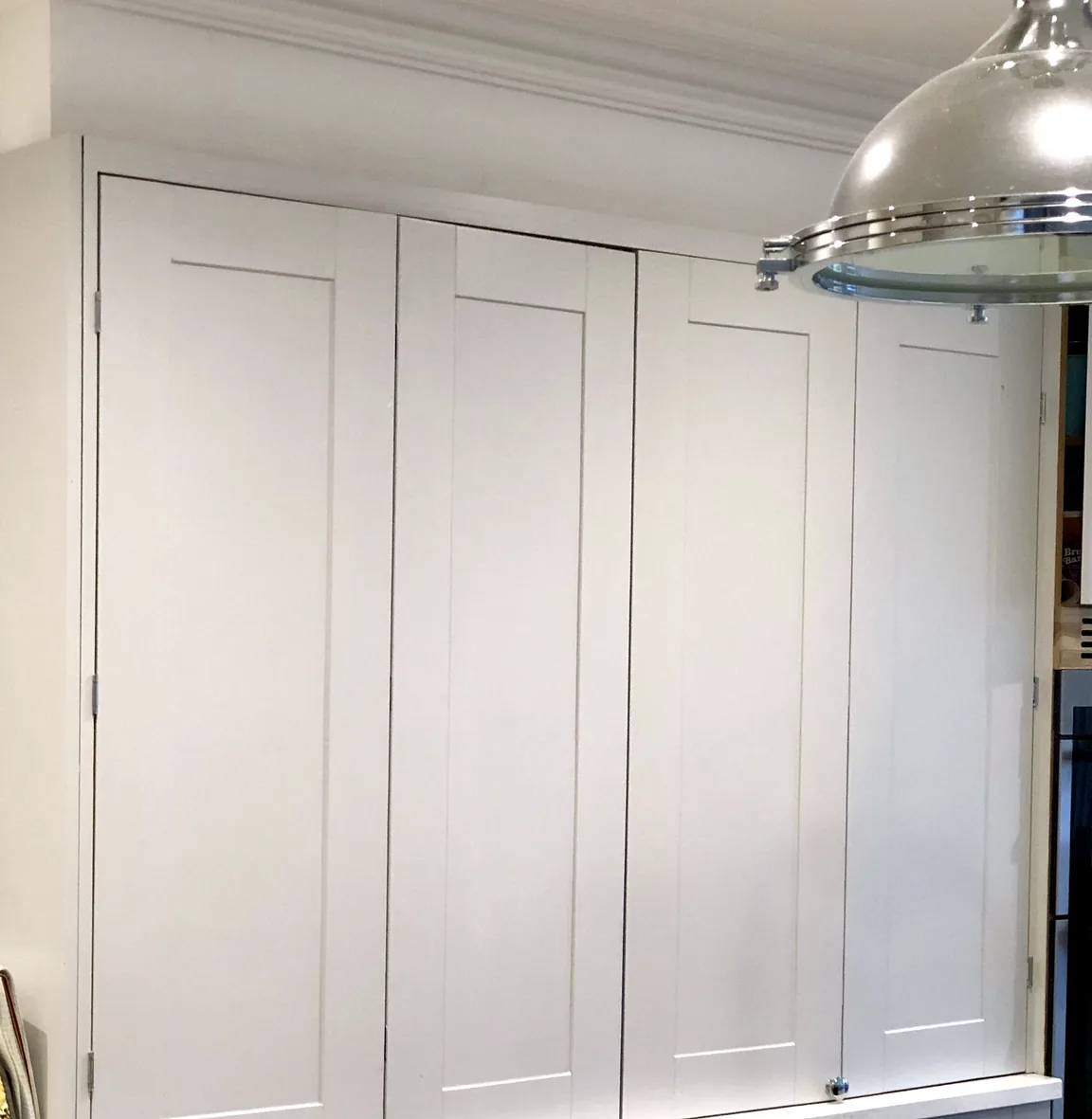 Four pale shaker-style cupboard doors closed above the worktop beneath a cornice.