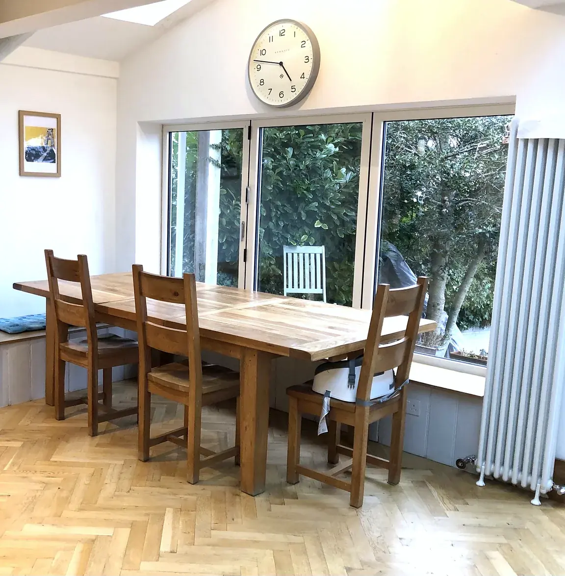 Dining area with an oak table, herringbone floor, a rooflight and bi-fold glazed doors to the garden.